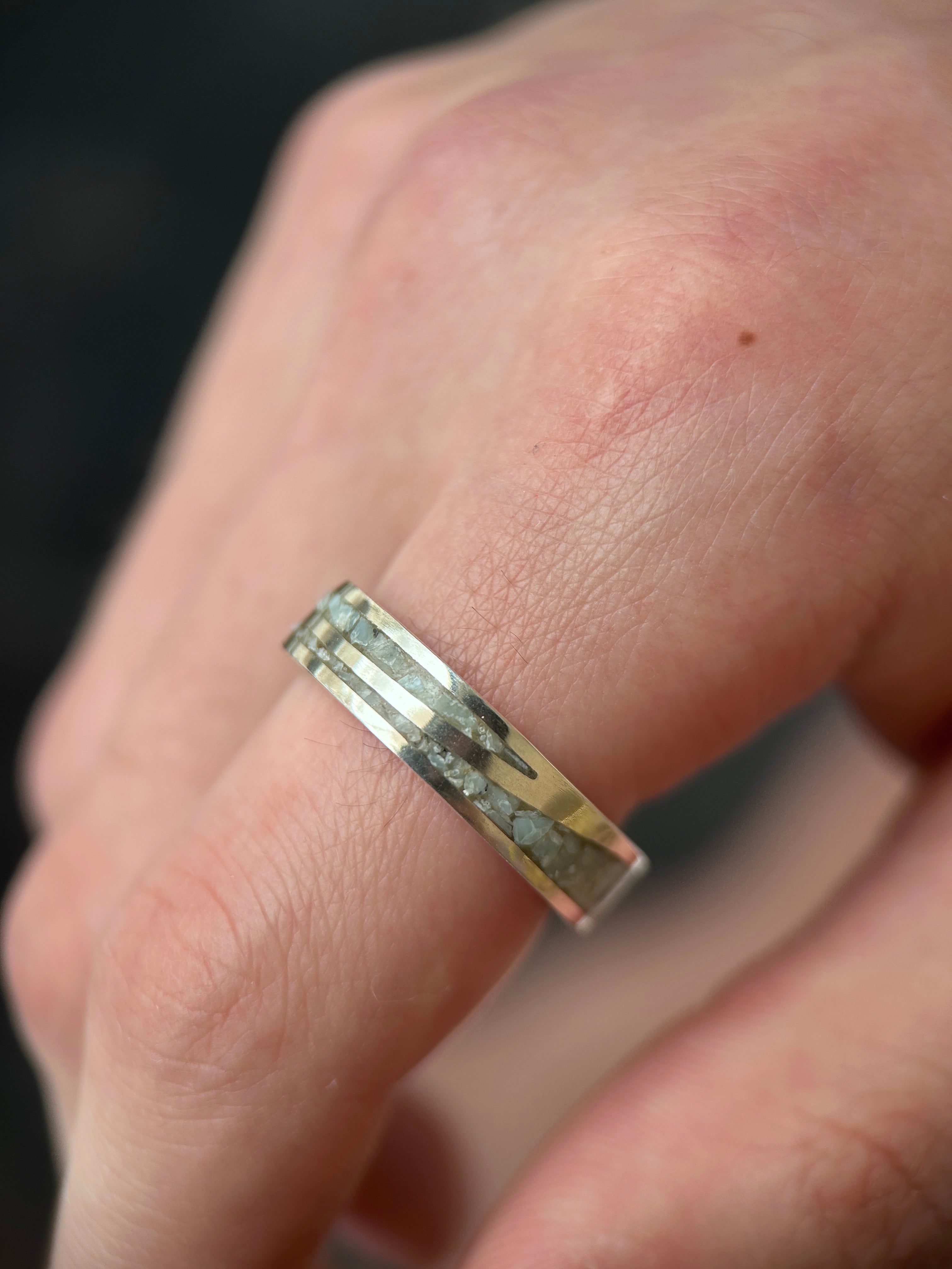 ring with embedded stones on a finger against a blurred background