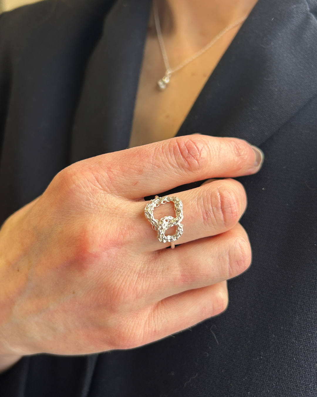 Hand wearing a silver ring with a dark background