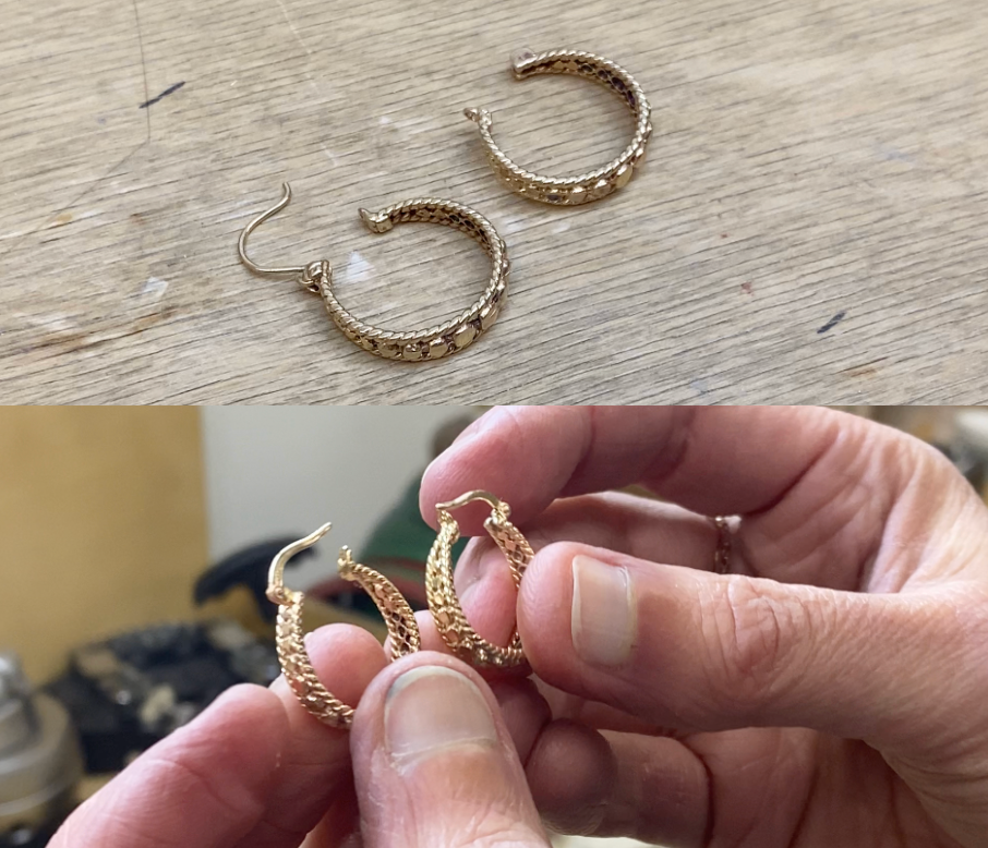 Gold hoop earrings on a wooden surface with a hand holding another pair of earrings.