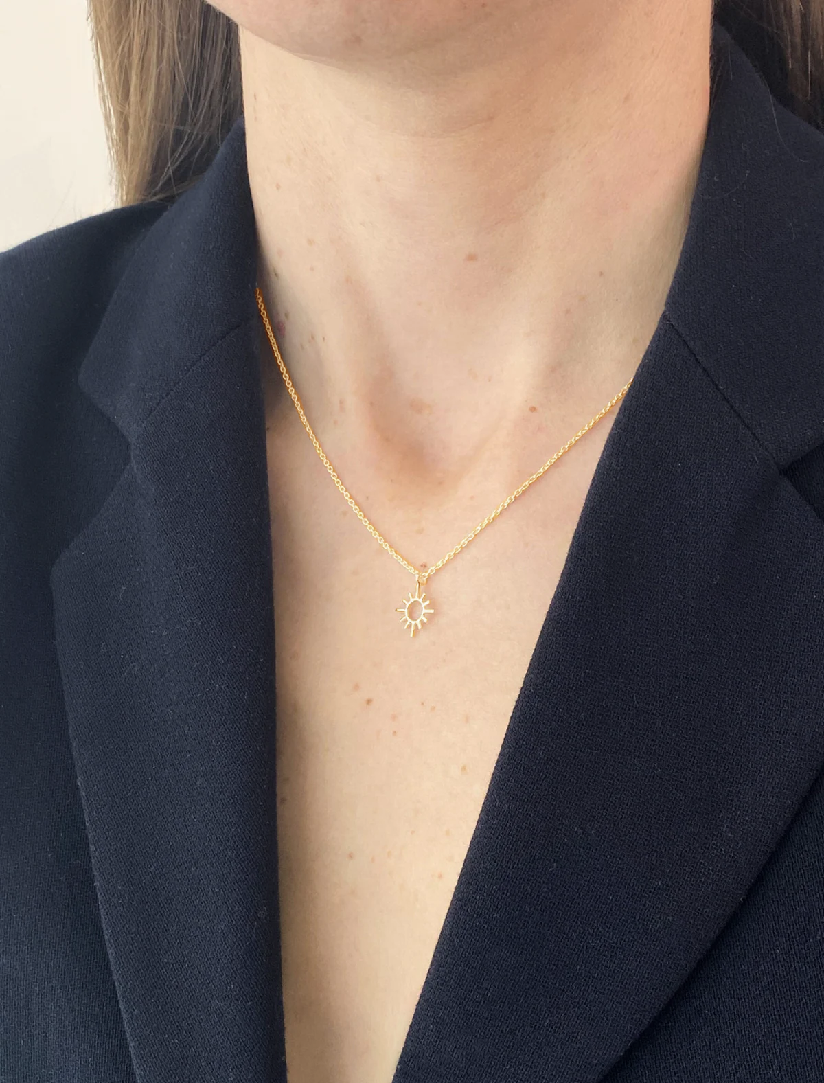 Gold necklace worn by a person with a dark blazer